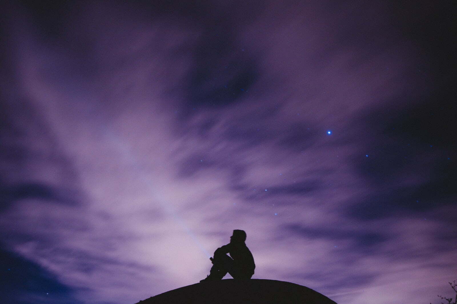 person sitting on black surface looking to sky