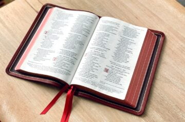 an open book on a table with a red ribbon