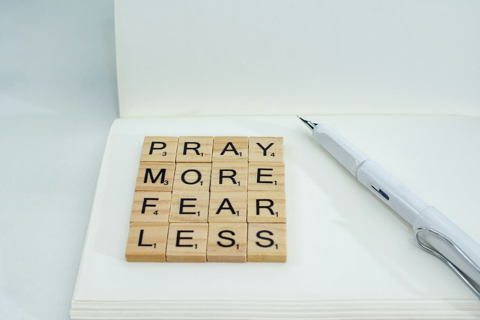 a wooden scrabble that says pray more fear less
