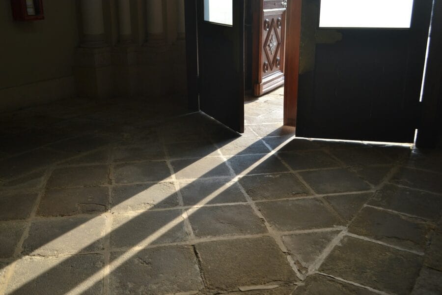 Sunlight streams across a tiled floor through open doors.