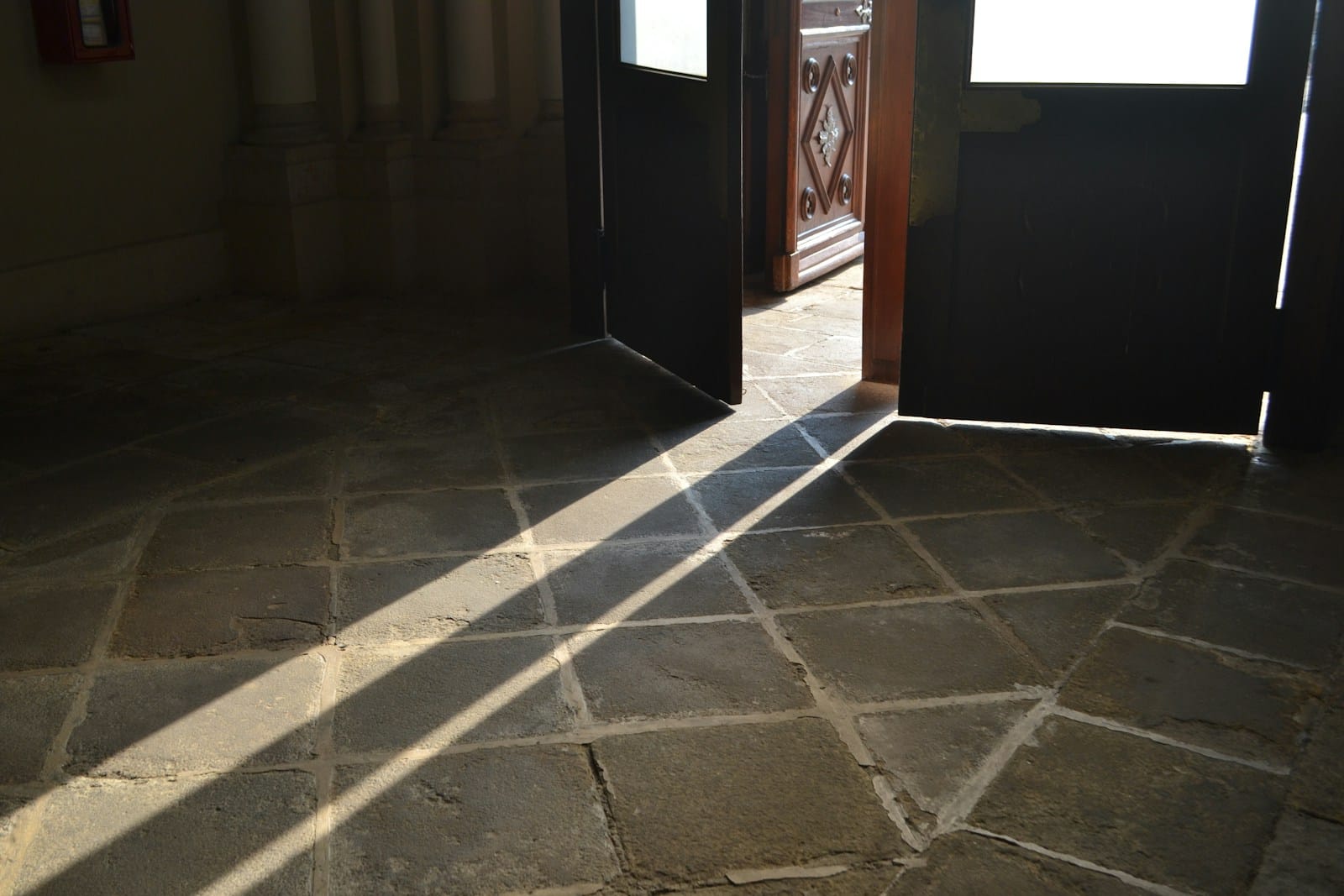 Sunlight streams across a tiled floor through open doors.
